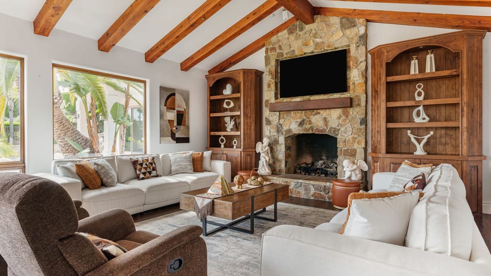 Warm, rustic‑modern living room with a stone fireplace, exposed beams, and cozy seating for relaxed Temecula evenings.
