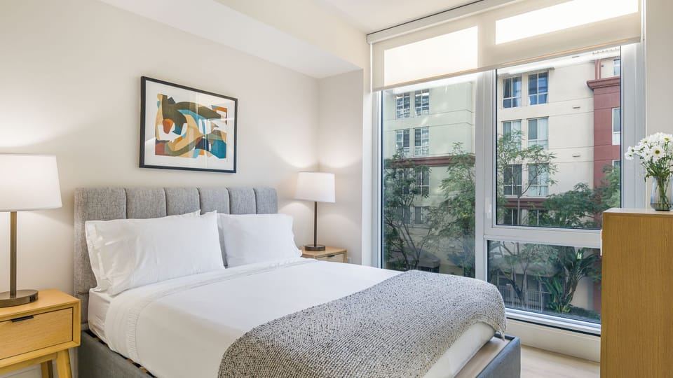 Retreat to a stylish sanctuary featuring plush bedding and expansive windows for natural light.
