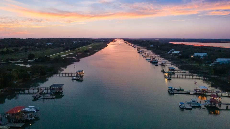 Stunning waterfront canal at sunrise, lined with docks and boats in a peaceful coastal setting.