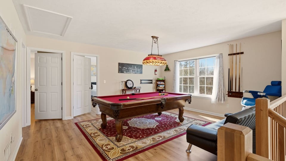 Classic red‑felt pool table, cozy seating, and plenty of natural light.