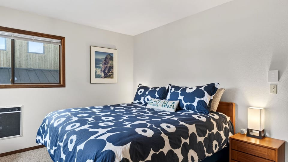 The primary bedroom features a king bed with a white, floral-patterned duvet.