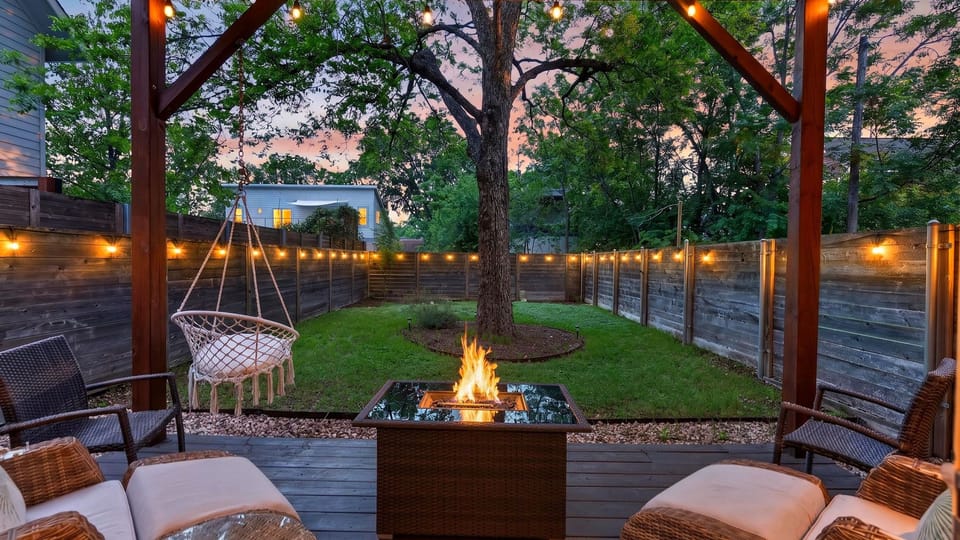 Cozy covered patio with a fire pit, string lights, and a private fenced yard for relaxed evenings outdoors.