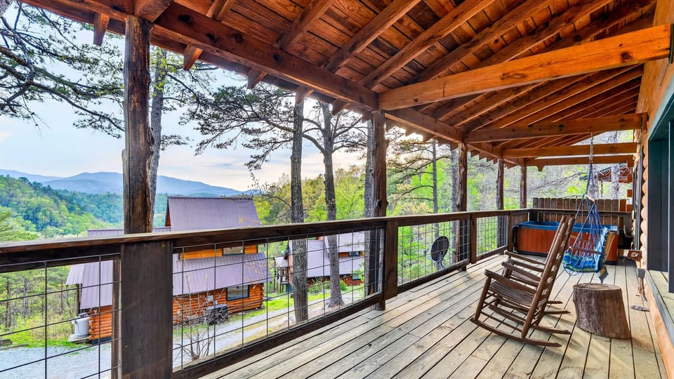 Rustic cabin porch with rocking chairs and a swing, opening to peaceful pines and rolling mountain views.