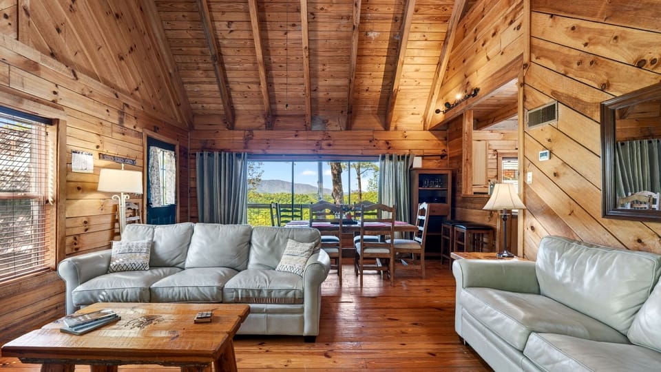 Warm wood interiors and an open-concept living space set the tone, with large windows framing peaceful mountain views just beyond the dining area.