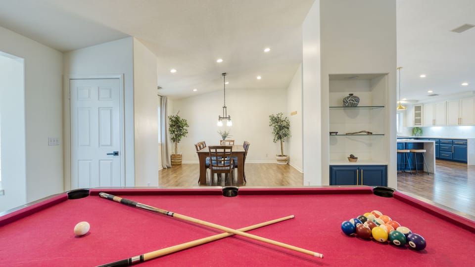 Bright entertainment area with a red pool table, open dining space, and a stylish modern kitchen. (Main House)