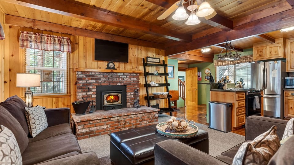 A warm, wood-lined living space with a fireplace and open layout sets the tone for a classic cabin stay.