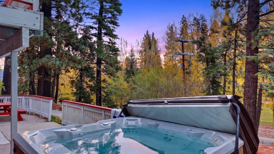 Private hot tub on the deck with serene forest views at sunset.