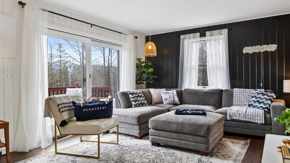 Bright, modern lounge with a cozy sectional and peaceful forest views. (The Hollow)