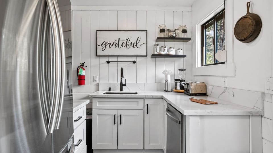 Bright and modern culinary space featuring white cabinetry and stainless steel accents.