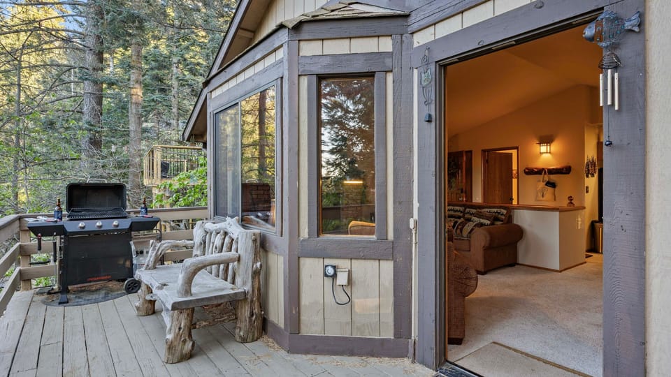 Step outside to a private forest deck with a gas grill, rustic seating, and easy indoor-outdoor cabin living.