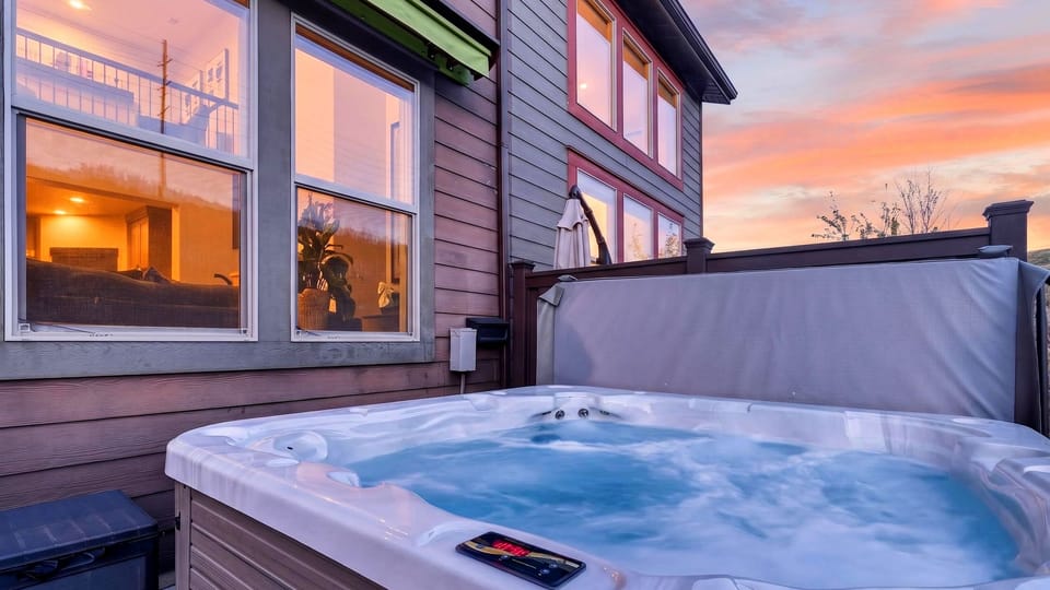Relax in the private outdoor hot tub while enjoying vibrant sunset views over the mountain ridgeline.