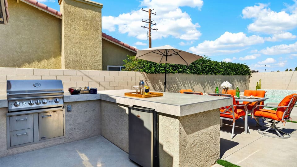 Outdoor entertainer's kitchen equipped with a built-in stainless steel grill, ample counter space, and a mini-fridge.
