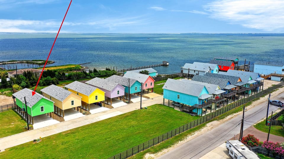 Aerial view of the colorful bayfront cottages with your stay highlighted just moments from the water.