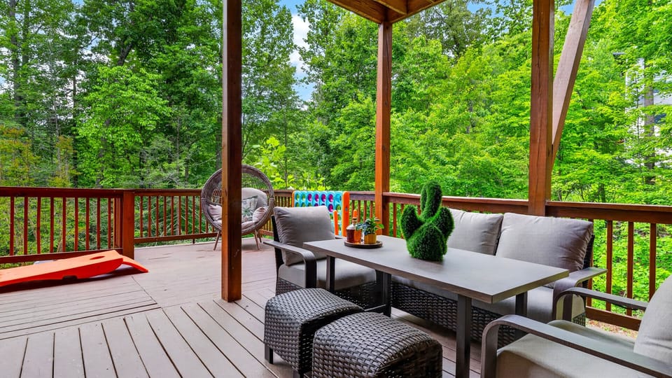 Covered deck lounge with forest views, cozy seating, and games for easy outdoor fun.