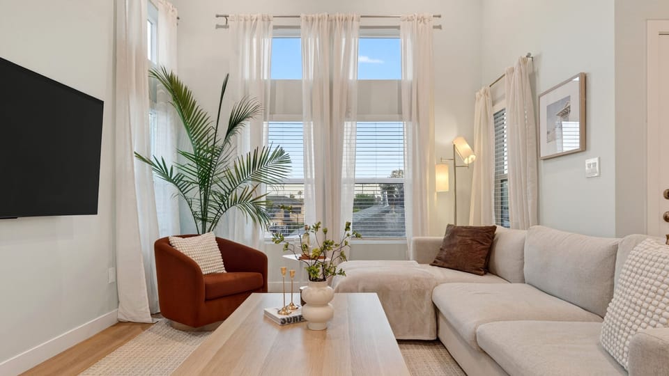 Bright living room with soaring windows, cozy seating, and a relaxed coastal feel.