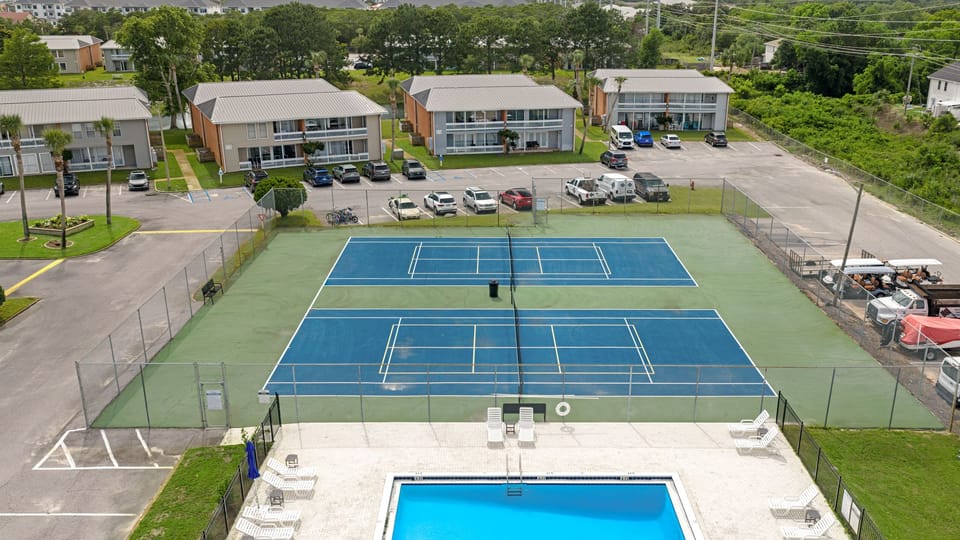 Aerial view of the community's premier amenities, including full-sized tennis courts and a sparkling blue swimming pool.
