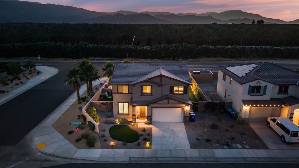 The home glows warmly at dusk, showing off its excellent architectural accent lighting.