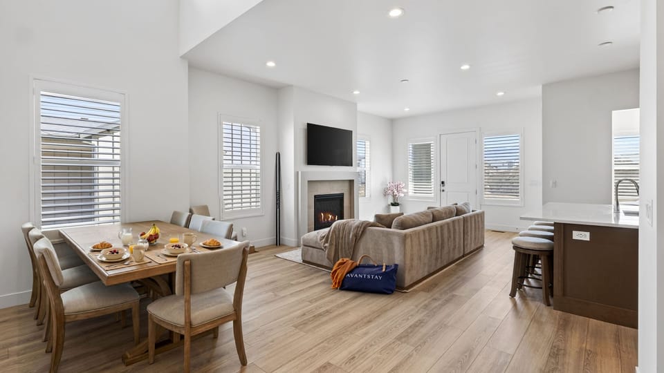 Bright open-concept living space with dining, kitchen seating, and a cozy fireplace lounge.