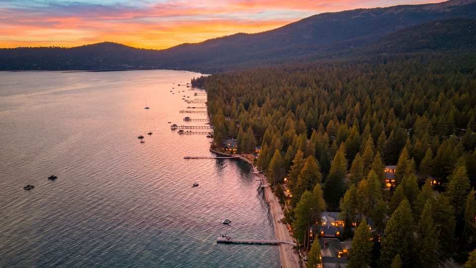 This expansive aerial view captures the dramatic contrast between the dense green forest and the vast, peaceful lake.
