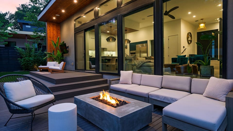 Glass walls connect the living room to a stylish terrace with deep seating and a modern fire table.