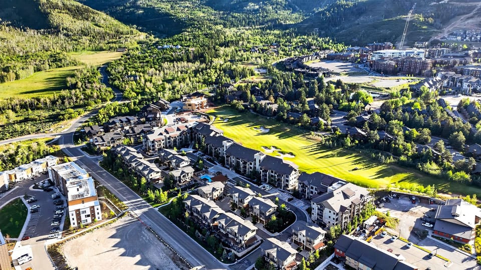 Expansive landscape drone shot capturing the intersection of the resort community, valley floors, and lush hillsides.