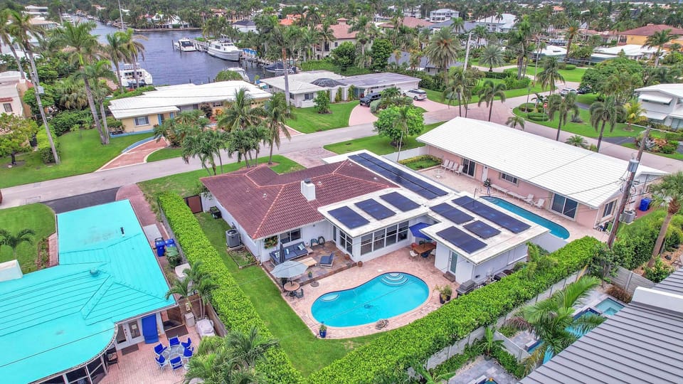 Aerial view showcasing the private pool, lush backyard, and nearby canal-lined neighborhood.