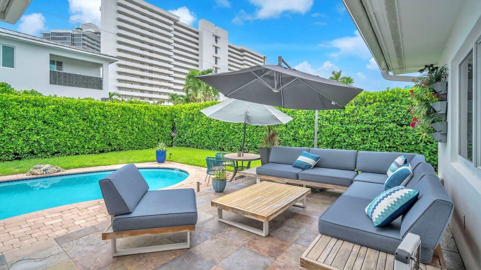 Poolside lounge area with shaded seating, tropical greenery, and a private tucked-away feel.