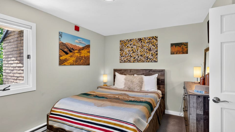 Bright and restful main bedroom suite accented by vibrant landscape artwork.