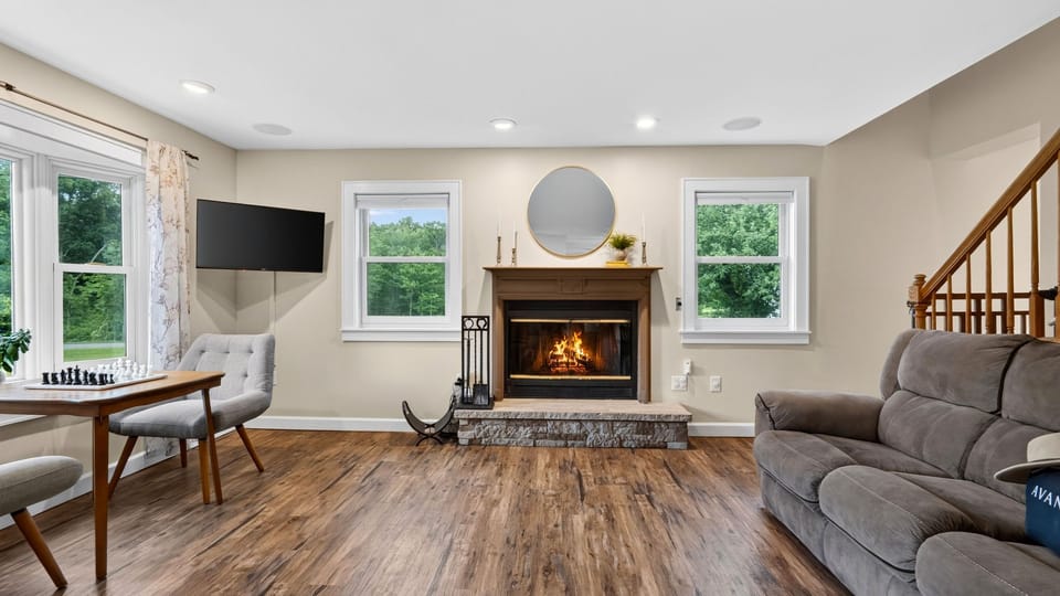 Cozy up by the stone-accented fireplace in this spacious living room framed by bright windows.