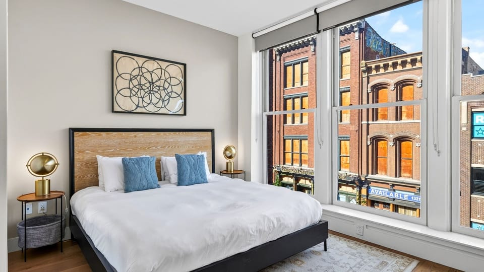 Bright and spacious bedroom featuring large windows, modern decor, and comfortable bedding.