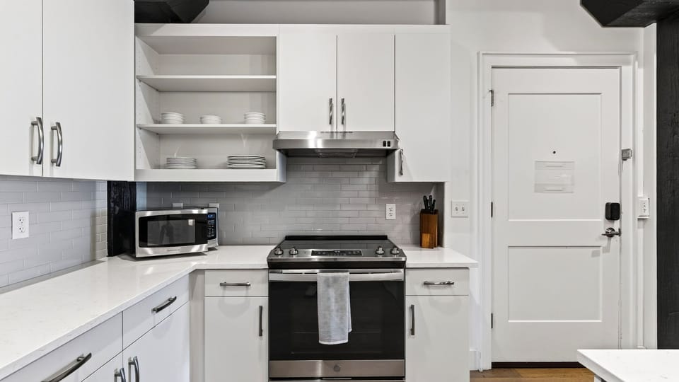 Clean, fully equipped modern kitchen with stainless steel appliances, gas range, and white cabinetry.