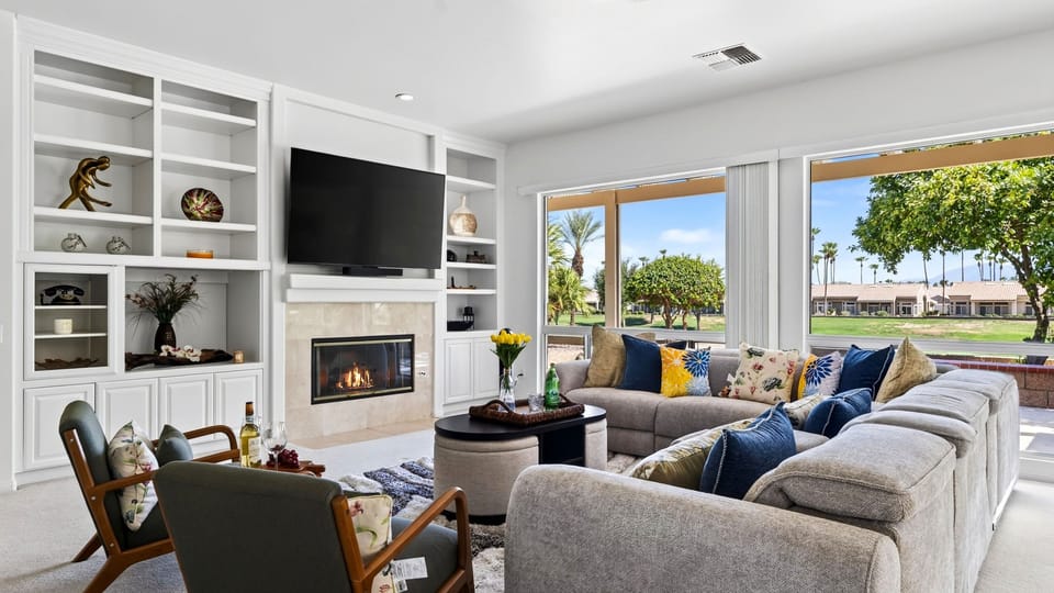 Gather in the bright living room, complete with a fireplace, large TV, and panoramic golf course views.