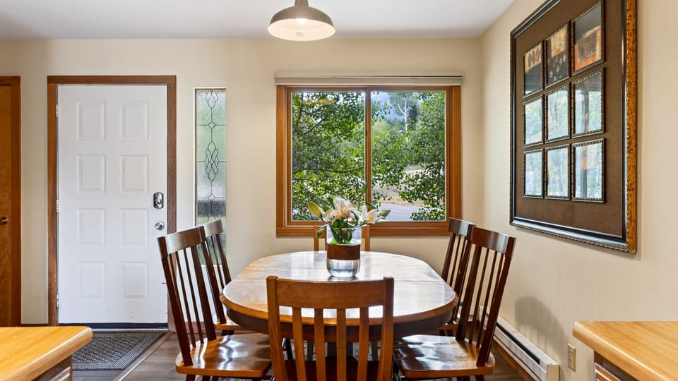 Dining area surrounded by large windows and mountain views.