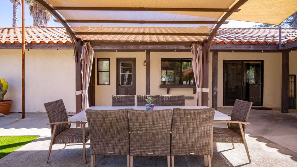 Covered outdoor dining patio with a wooden pergola and large dining table.