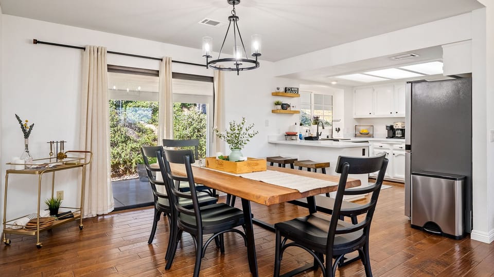 Covered patio with a wood dining table, lounge area, and grill