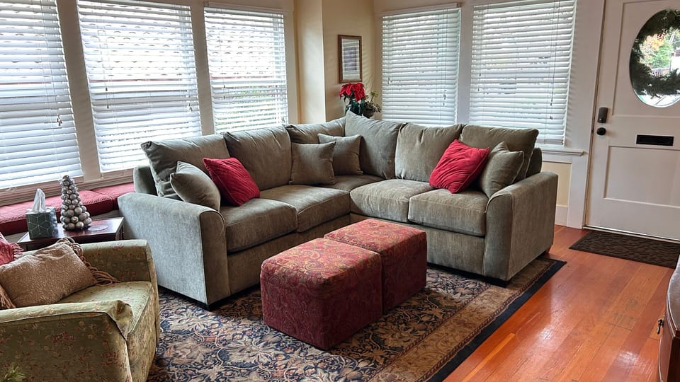 A bright living room with plush seating, warm wood floors, and abundant windows creates an inviting place to unwind.