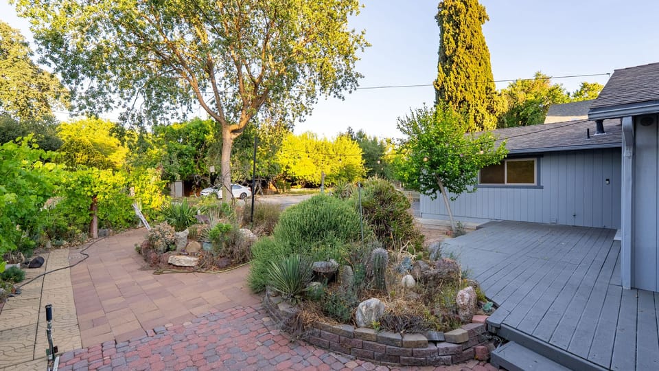 Backyard patio beside layered garden beds and a raised deck