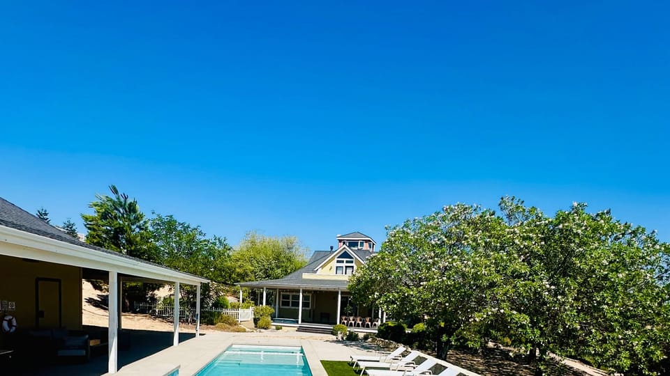 Pool and raised spa framed by loungers and open countryside views.