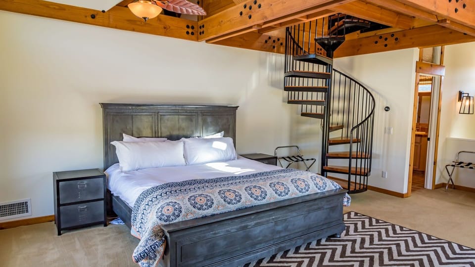 Spacious bedroom featuring a wrought-iron bed and spiral staircase to the loft.