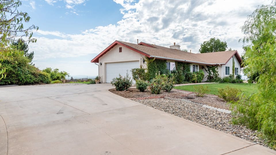 A wide driveway leads to the attached garage and front lawn.