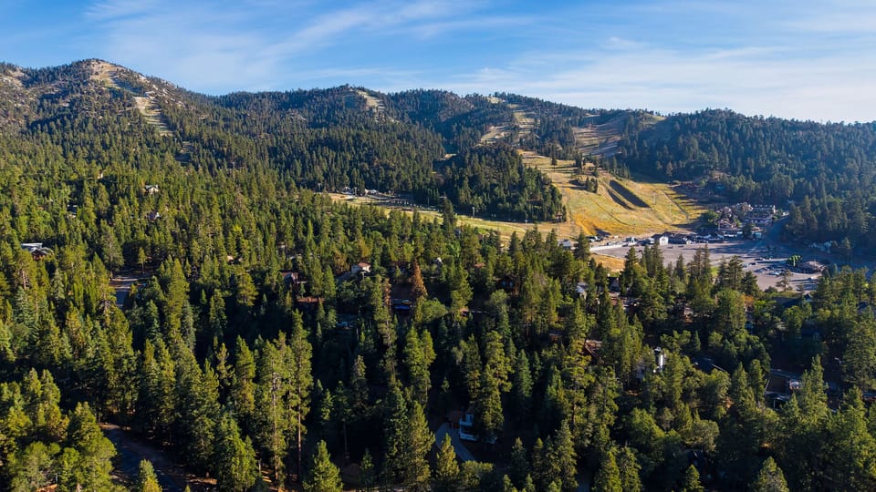 Wide aerial landscape view showing vast forests and distant mountain peaks.