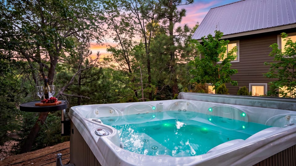 Outdoor hot tub on the wooden deck surrounded by trees.