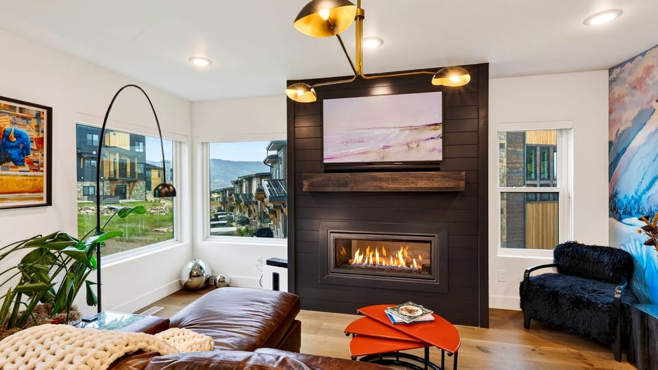 Main living area with modern fireplace, wall-mounted TV, and leather sofa.