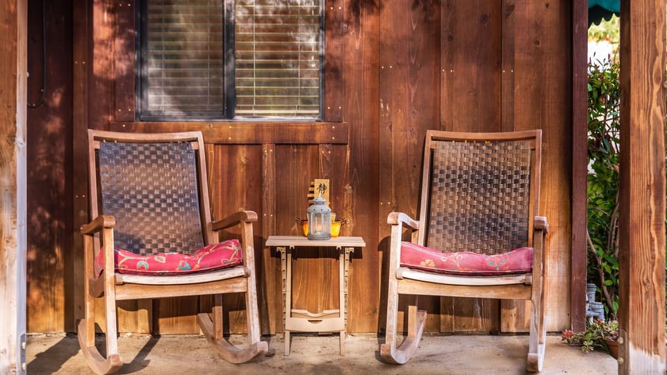 Outdoor porch with two wooden rocking chairs and a small accent table.