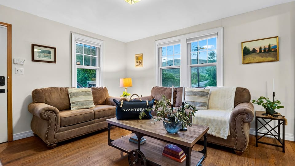Bright living room with cozy seating, hardwood floors, and mountain views through the windows.