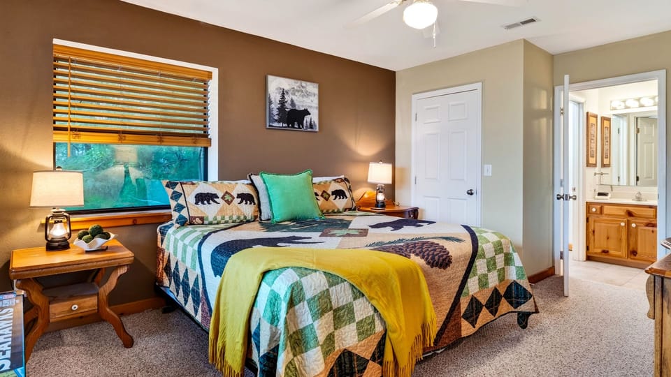 Bedroom 3 with wood paneling, a colorful patterned quilt, and a ceiling fan.