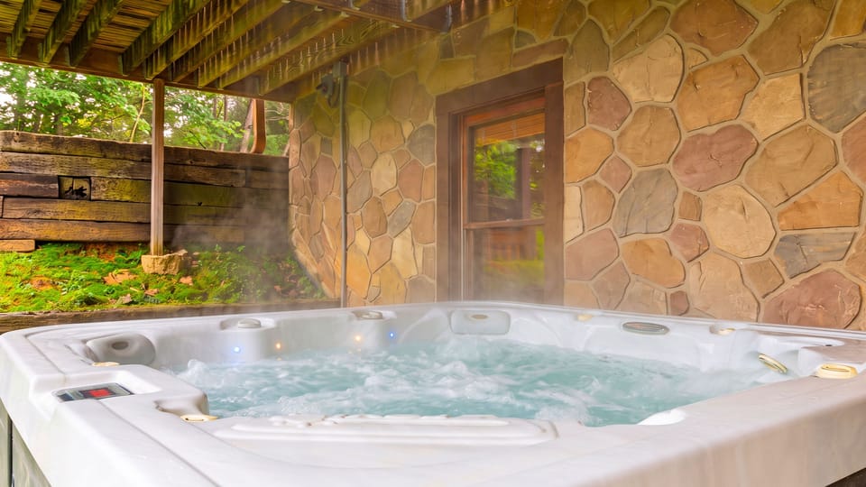 Covered hot tub beside a stone wall.