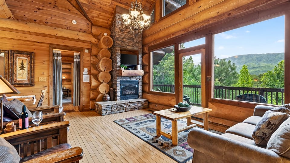 Vaulted living room with a stone fireplace and mountain views.