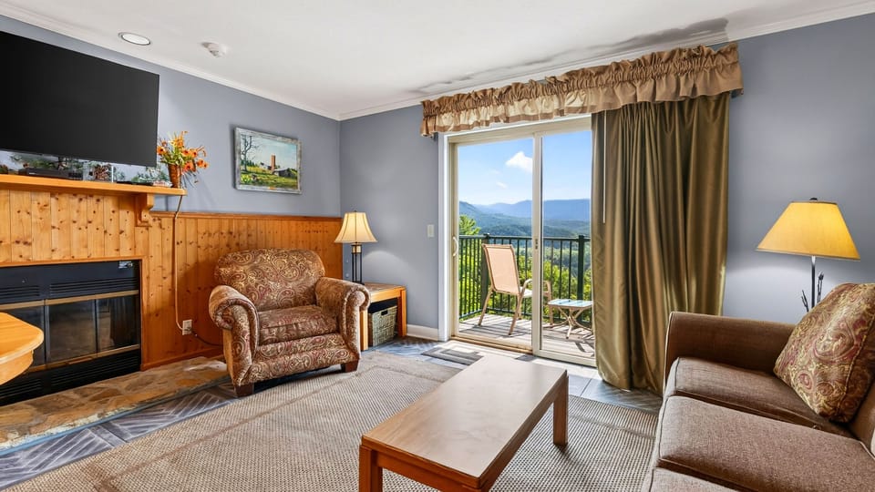 Bright living room with comfortable seating, a fireplace, and direct access to the mountain-view balcony.