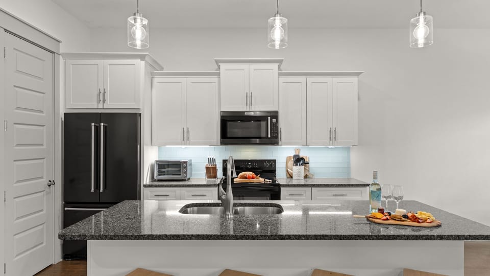 A polished coastal kitchen with a generous island, bright finishes, and space to gather over shared meals.